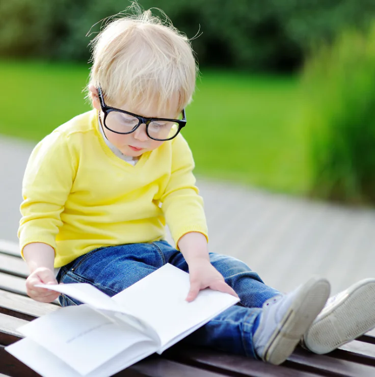 Young student smiling and reading a book – hero image for SAM's Seriously Addictive English literacy program